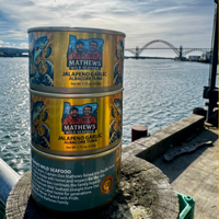 Mathews Wild Seafood Jalapeño & Garlic Albacore Tuna set against the Yaquina Bay Bridge, celebrating sustainably caught Oregon Coast seafood.